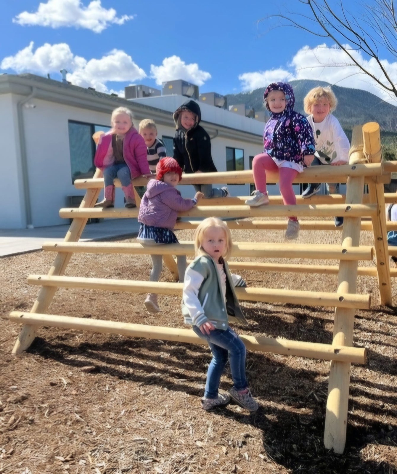 Funshine children exploring the wooden climbing structures in their outdoor classroom