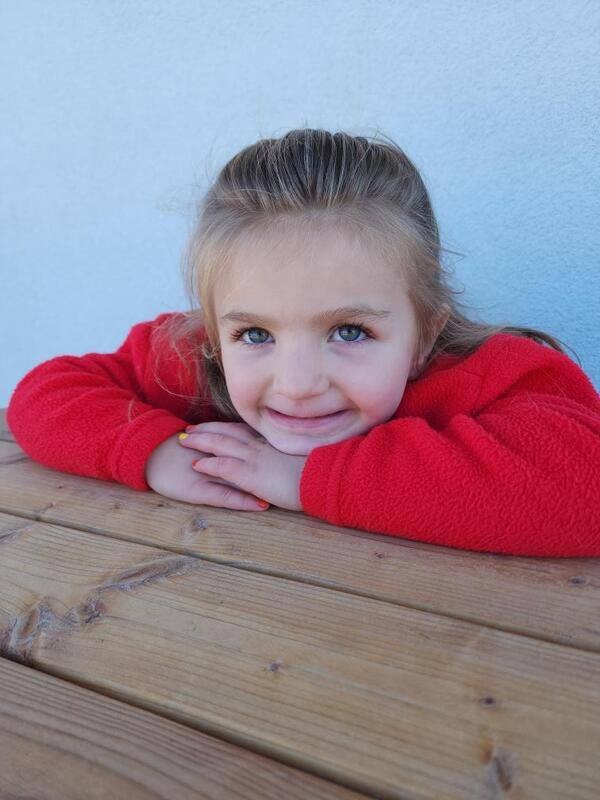 A smiling child leaning on the wooden outdoor play structure