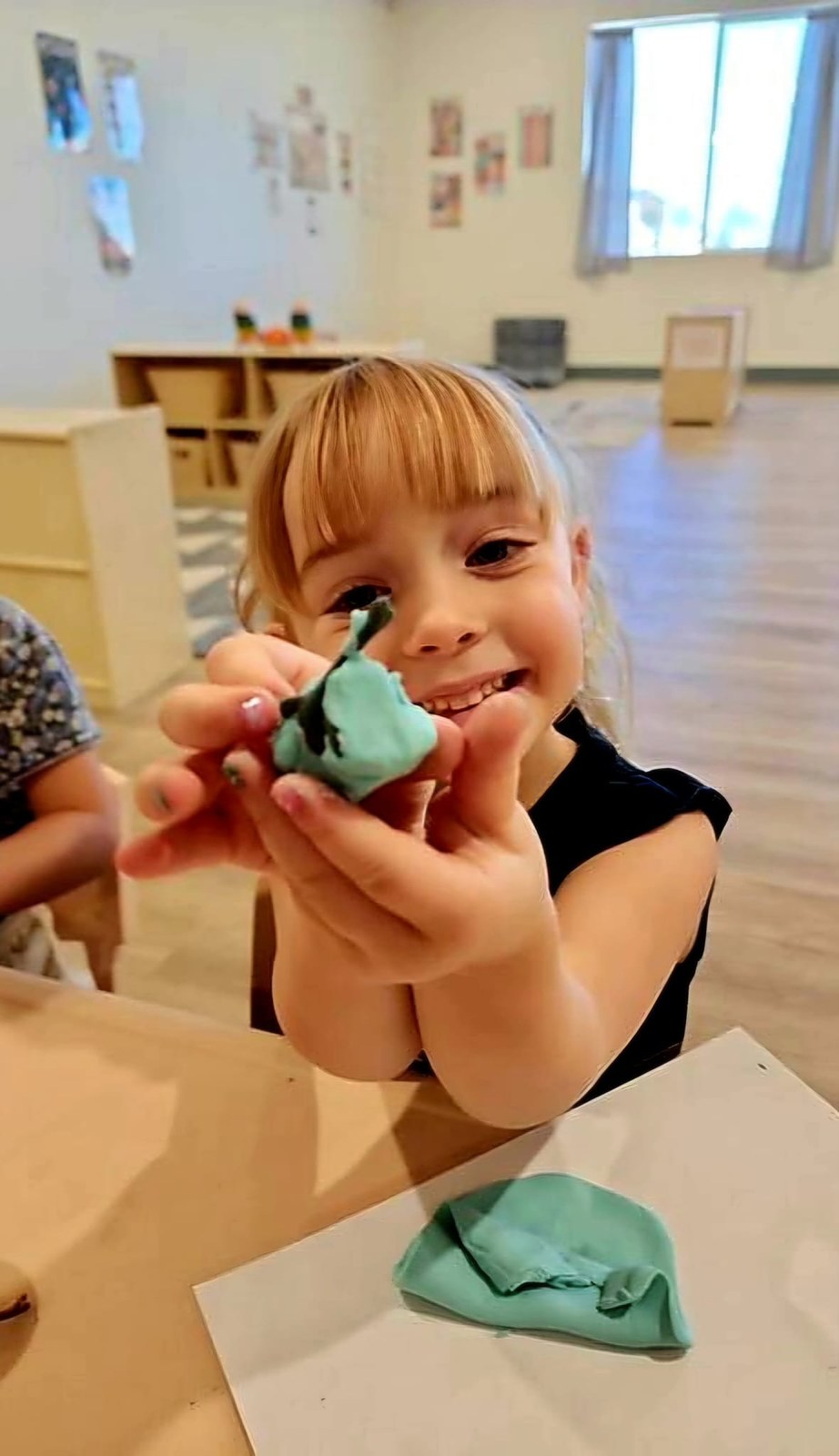A Funshine child proudly showing a colorful clay creation